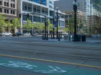 an empty street with buildings and parked cars on the sidewalks and green lanes on the sidewalk