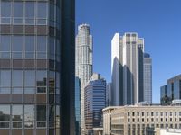 some tall buildings near each other in the middle of a city of skyscrapers with glass windows