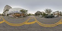 a panoramic image of cars in front of a building with a sky background