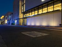 a street with a light on in front of a building at night, showing the entrance to a museum