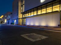 a street with a light on in front of a building at night, showing the entrance to a museum