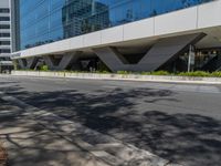 empty sidewalk next to large building in urban area of city scene with building in reflection