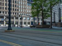 the green paint is painted on a bike path in front of an office building and large, trees