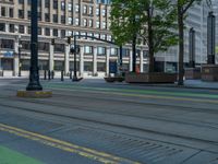 the green paint is painted on a bike path in front of an office building and large, trees