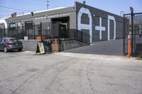 a black car parked outside of the garage store front entrance of a coffee shop with grey, white and blue signage