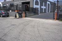 a black car parked outside of the garage store front entrance of a coffee shop with grey, white and blue signage