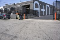 a black car parked outside of the garage store front entrance of a coffee shop with grey, white and blue signage