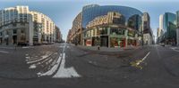 a wide angle shot of an intersection in a big city with many buildings around it