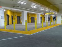 empty parking garage filled with vehicles and yellow signs on the curb of the building with closed doors