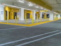 empty parking garage filled with vehicles and yellow signs on the curb of the building with closed doors