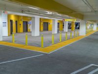 empty parking garage filled with vehicles and yellow signs on the curb of the building with closed doors