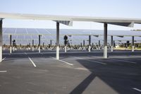 a parking lot with rows of solar panels on top and a sky line in the background