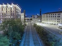 a train track and some buildings on the side of a road at night time in the city