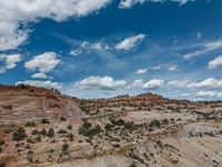 a vast mountainous landscape with blue skies above the tops and some brown dirt fields below