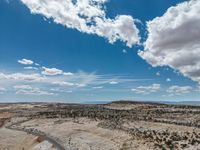 a vast mountainous landscape with blue skies above the tops and some brown dirt fields below