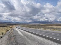 an empty empty country road with snowy mountains in the background in the desert, on a clear day