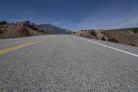 the road is empty in an open area on a sunny day in the desert with mountain views