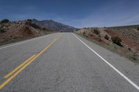 the road is empty in an open area on a sunny day in the desert with mountain views