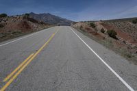 the road is empty in an open area on a sunny day in the desert with mountain views