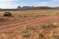 a dirt road going through the desert with a mountain in the distance in background in the foreground