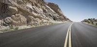 an empty highway with no traffic on both sides of it in the desert area with rocks and grass