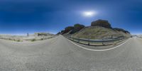 a panorama lens view of the road and mountains at the bottom of it, taken with a fish eye lens