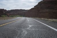 a person riding a motorcycle along a narrow road through rocks and sand cliffs a grassy area on both sides