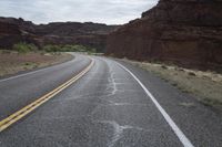 a person riding a motorcycle along a narrow road through rocks and sand cliffs a grassy area on both sides