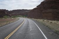 a person riding a motorcycle along a narrow road through rocks and sand cliffs a grassy area on both sides