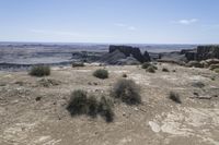 a barren field with rocks and scrub grass in the background on a partly clear day