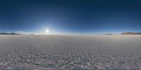 a snow covered plain with a bright sun in the background next to some mountains and mountains