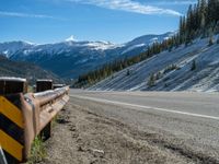 a scenic mountain road with a snow covered mountain behind it on a sunny day,