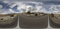 a wide angle of a road in the desert with the sky partially partly cloudy and no cars