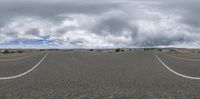 the empty street and white clouds against a cloudy sky in the middle of nowhere, as seen on fisheye glasses