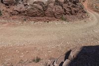 the motorcycle is on the side of the dirt road on the mountain top next to the rocks