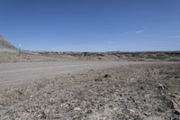 a dirt road is surrounded by some hills and desert like terrain as the vehicle sits on it