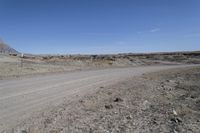 a dirt road is surrounded by some hills and desert like terrain as the vehicle sits on it