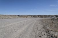 a dirt road is surrounded by some hills and desert like terrain as the vehicle sits on it