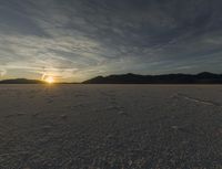 sunset on barren mountain landscape with tracks leading to a trail through the barren landscape,