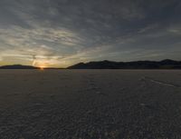 sunset on barren mountain landscape with tracks leading to a trail through the barren landscape,