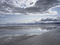 some very nice looking skies reflected in a wet beach surface, near a small beach