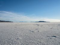 the desert with white and blue skies in the background, and footprints in the sand