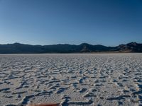 someone is taking their picture on the beach in desert area with mountains in the background