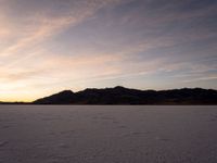 a large snowy area with many tracks and tracks on the ground at sunset time and hills behind it