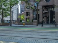 the green paint is painted on a bike path in front of an office building and large, trees