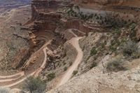 two motorcycles that are traveling down a dirt road between two rocky cliffs in the canyon