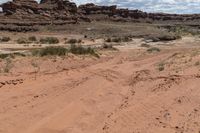 there is a motorcycle parked on the sand in the desert between two hills and large rock formations