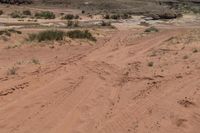 there is a motorcycle parked on the sand in the desert between two hills and large rock formations