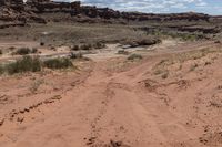 there is a motorcycle parked on the sand in the desert between two hills and large rock formations