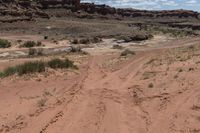 there is a motorcycle parked on the sand in the desert between two hills and large rock formations